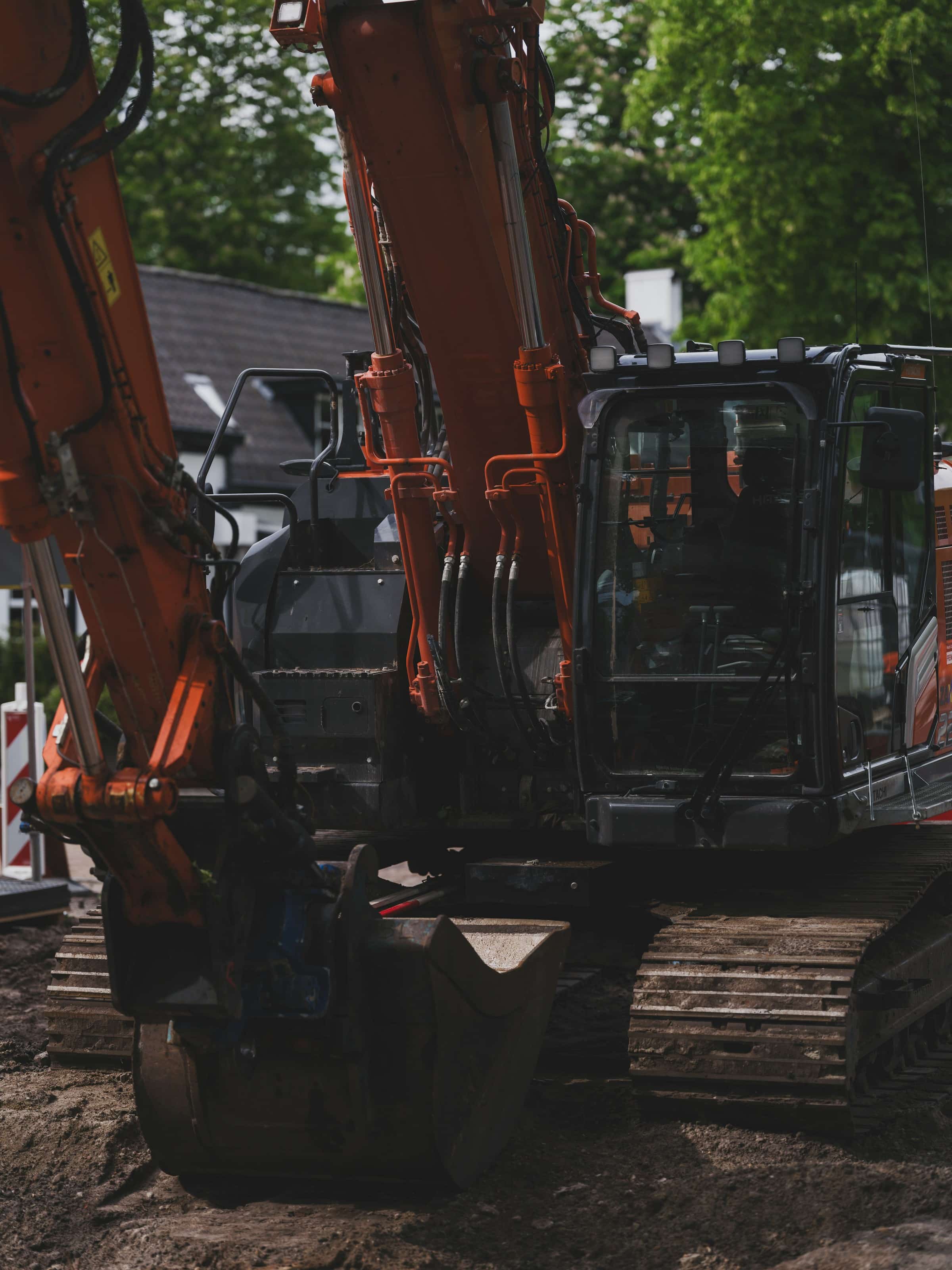 Graafmachine aan het werk in een woonstraat, met een rood-wit afzetbord